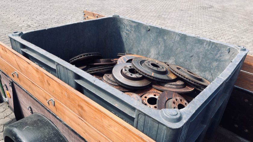 Eine graue NEUWERT-Box voller Bremsscheiben auf einem Anhänger