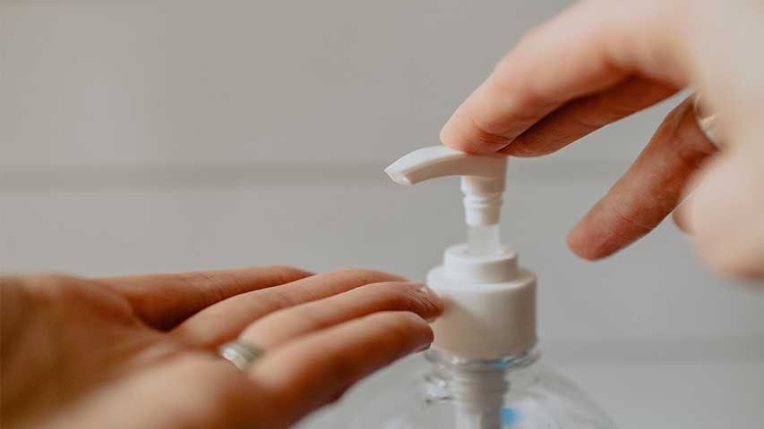 Die Hände einer Person nutzen einen Desinfektionsspender bei NeuWert Braunschweig.